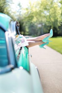 woman's legs hanging out the side of a mint green classic car