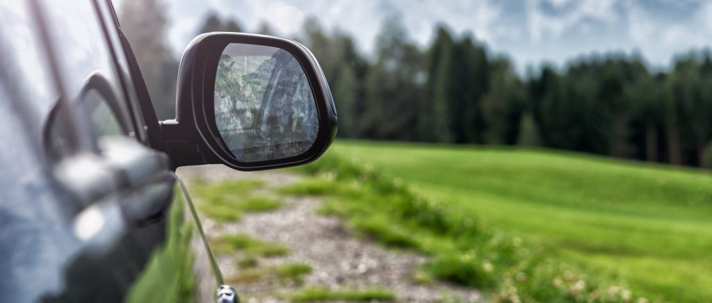A car drives on an open country road at dusk.