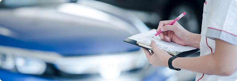 A person filling out the checklist in front of a car